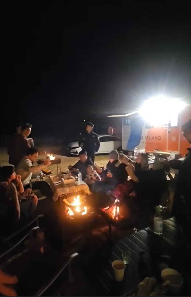 카라반 앞 모닥불에 둘러앉은 가족