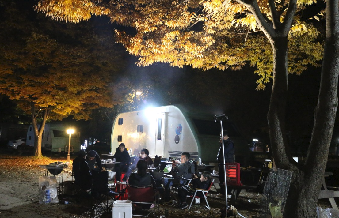 단풍 아래 카라반과 가족의 캠핑 밤